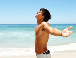 Portrait of a relaxed young man with his hands stretched, standing at the beach