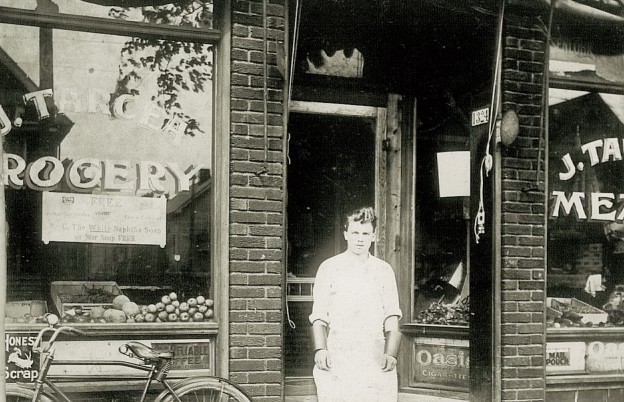 Ieronim Budac în fața grocery store-ului lui John Tarcea, paravanul pentru cel mai mare laborator clandestin de producție de rachiu din Chicago în perioada Prohibiției (aprox. 1925).