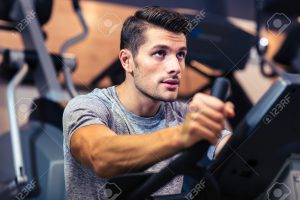Portrait of a handsome man workout on a fitness machine at gym