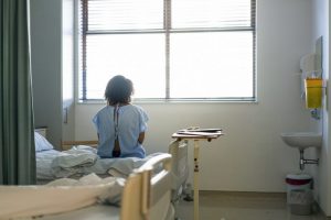 Lonely female patient sitting on hospital bed