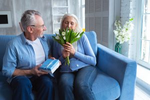 The old man giving a gift and flowers to a woman
