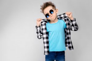 handsome-boy-plaid-shirt-blue-shirt-jeans-stands-gray-background-boy-is-wearing-round-glasses-redhead-boy-holding-his-fingers-collar-shirt-1