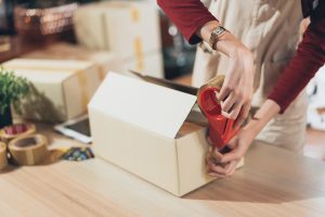Small business shop owner taping box packaging before shipping