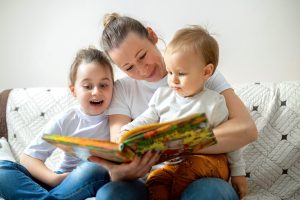 mom-her-two-children-are-reading-book-home-sofa-happy-smiling