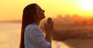 Profile of a woman praying at sunset