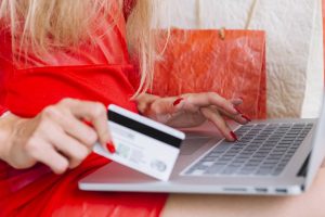 woman-red-sitting-with-laptop-card-near-shopping-bags_wp