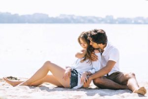 boyfriend hugging girlfriend on sandy city beach near river